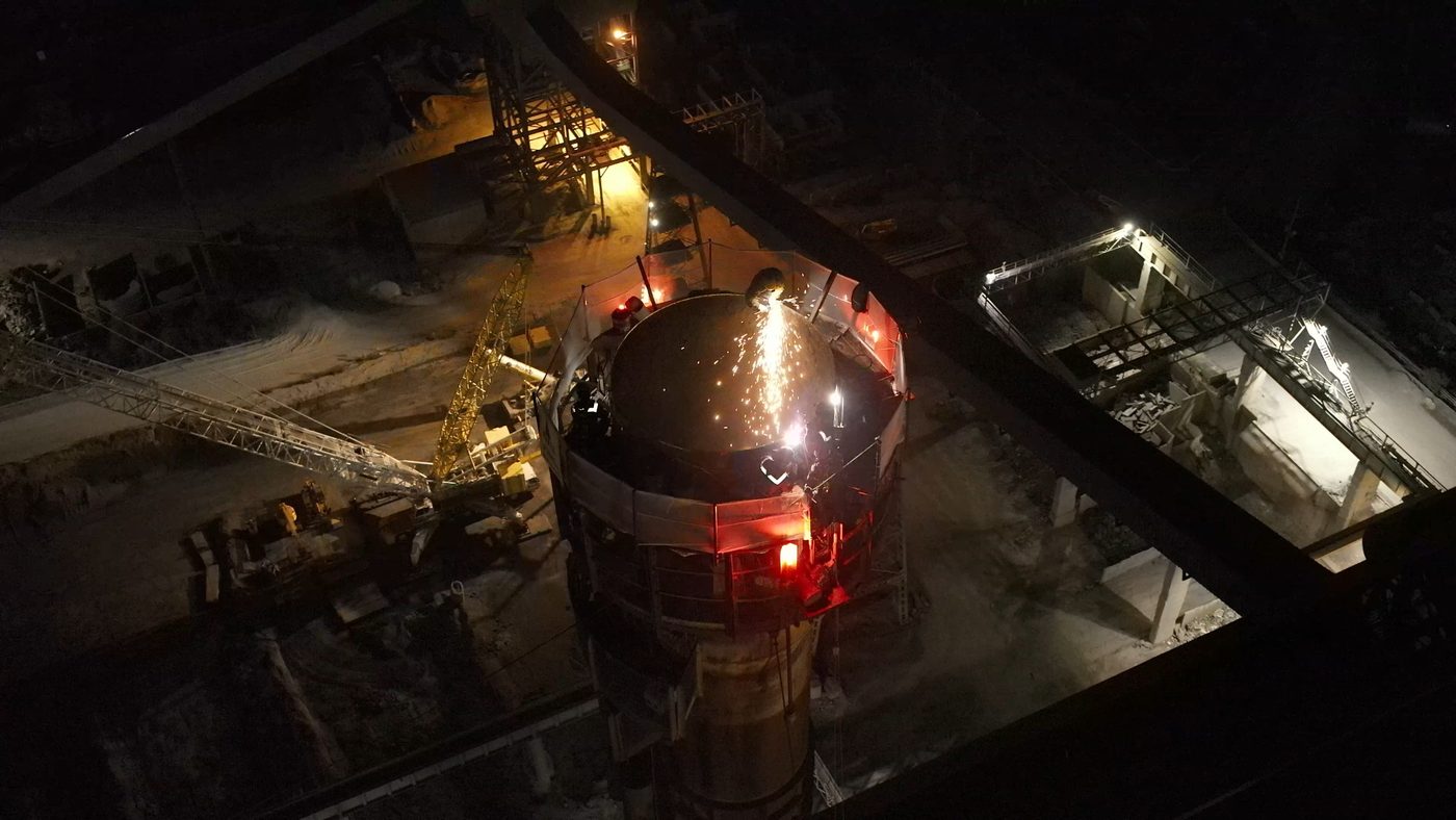 Découpe de nuit au sommet d'une torchère vue par drone, gerbes d'étincelles visibles